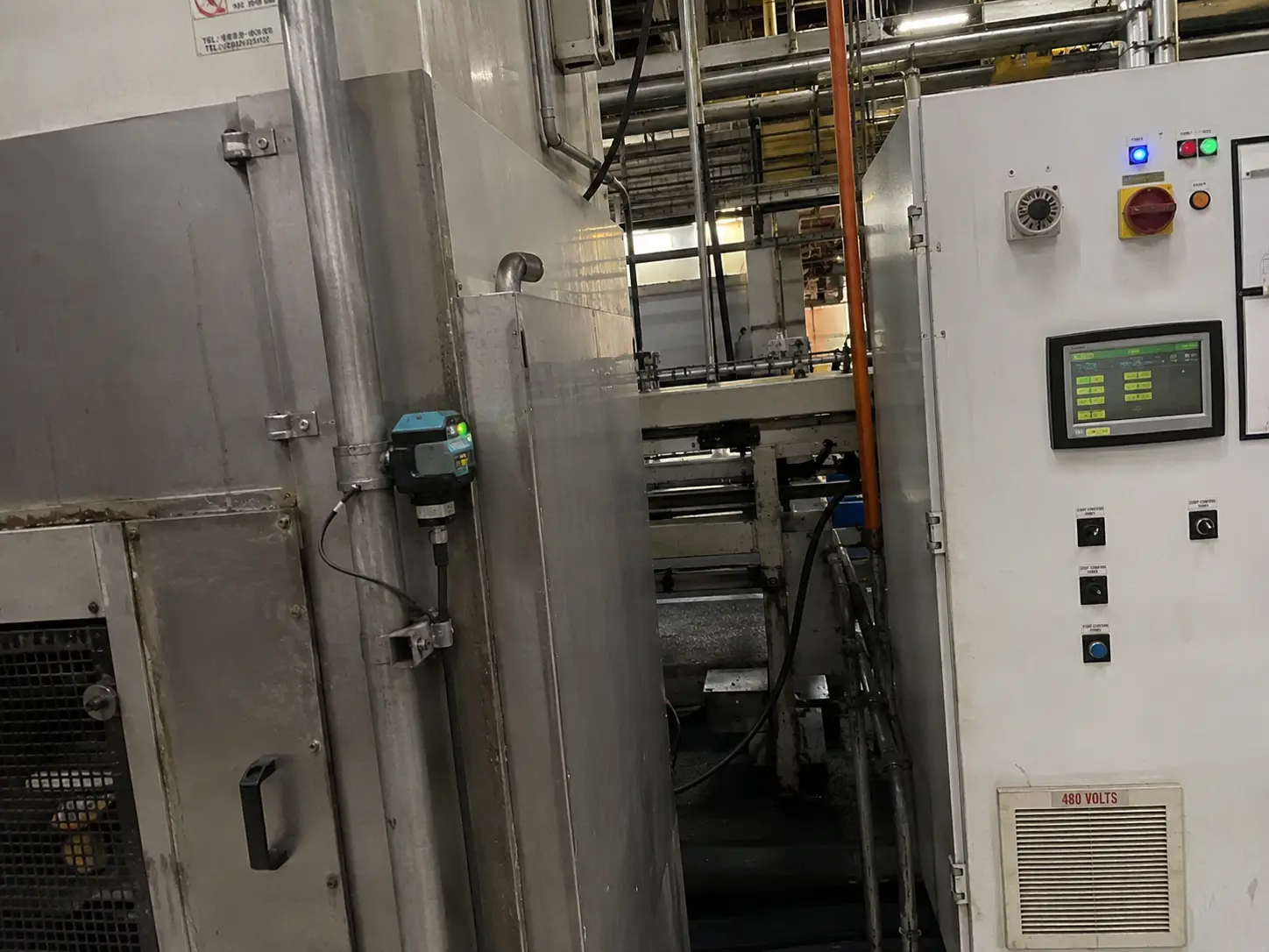 Scorcio di un impianto industriale con tubazioni e un sensore di monitoraggio installato su un macchinario